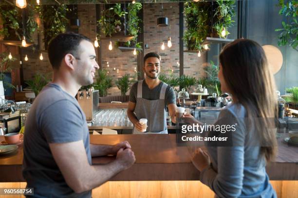 cameriere che serve caffè a una coppia in un bar - man eating at diner counter foto e immagini stock