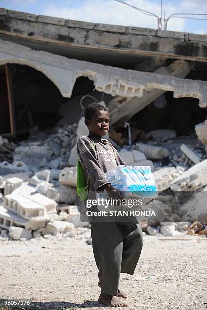 Boy from the destroyed Chirstian Orphanage of Bonne Nouvelle carries water distributed by a Sri Lankan United Nations unit January 23, 2010 in...
