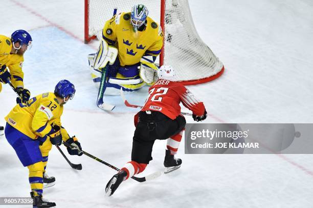 Switzerland's Simon Moser and Sweden's goalkeeper Anders Nilsson vie during the final match Sweden vs Switzerland of the 2018 IIHF Ice Hockey World...