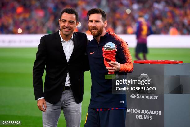 Barcelona's Argentinian forward Lionel Messi receives the player of the month trophy from Barcelona's former Spanish midfielder Xavi before the...