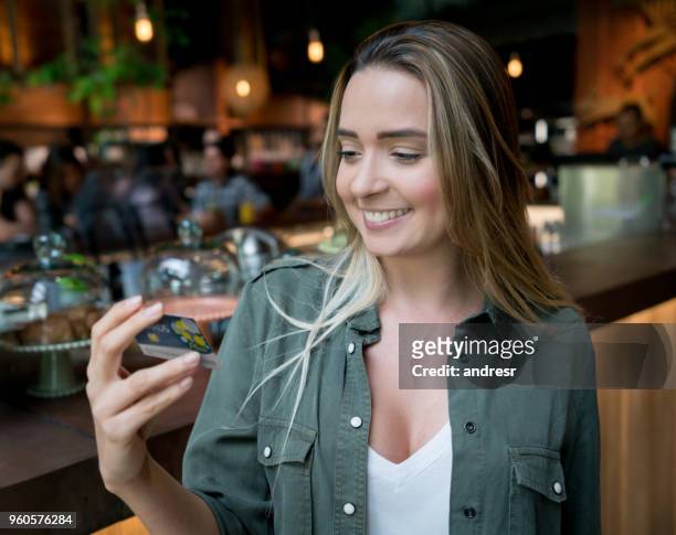 female customer holding a rewards card at a food market - loyalty cards stock pictures, royalty-free photos & images