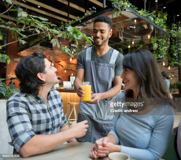 cameriere che serve bevande a una coppia in un bar - man eating at diner counter foto e immagini stock