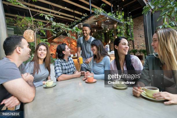cameriere che serve bevande a un gruppo di amici in un bar - man eating at diner counter foto e immagini stock