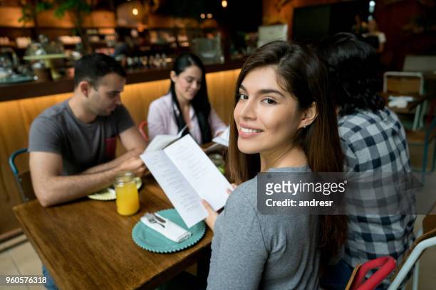 donna che mangia con un gruppo di amici in un ristorante - man eating at diner counter foto e immagini stock
