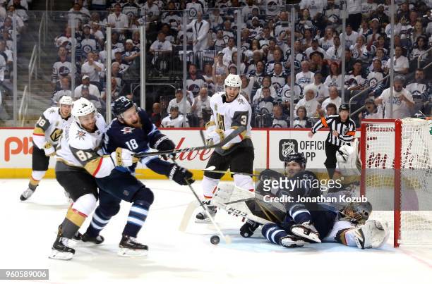 Bryan Little of the Winnipeg Jets tries to corral the loose puck as teammate Jack Roslovic falls into goaltender Marc-Andre Fleury of the Vegas...