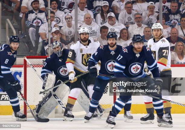 Goaltender Connor Hellebuyck of the Winnipeg Jets looks around a screen set by Alex Tuch of the Vegas Golden Knights and teammates Josh Morrissey and...