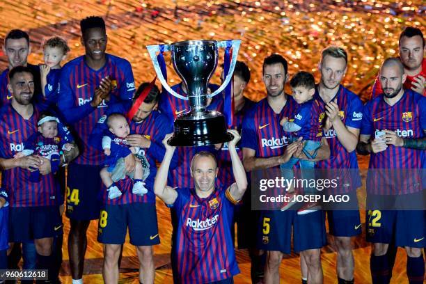 Barcelona's Spanish midfielder Andres Iniesta raises the Liga trophy during a tribute after the Spanish league football match between FC Barcelona...