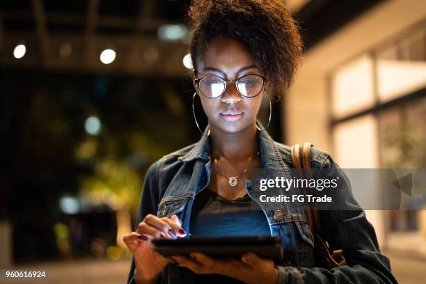 junge schwarze frau mit afro-frisur mit digital-tablette im städtischen hintergrund - alternative lifestyles stock-fotos und bilder