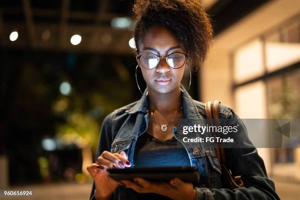 young black woman with afro hairstyle using digital tablet in urban background - latin america cities stock pictures, royalty-free photos & images