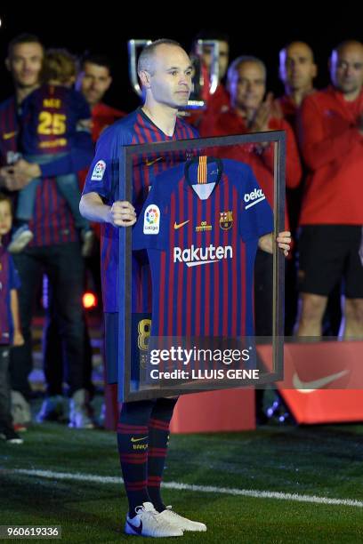 Barcelona's Spanish midfielder Andres Iniesta poses with a framed jersey during a tribute at the end of the Spanish league football match between FC...