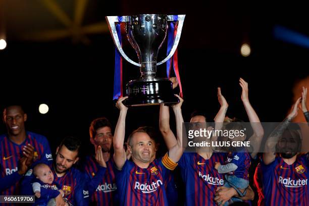 Barcelona's Spanish midfielder Andres Iniesta raises the Liga trophy during a tribute at the end of the Spanish league football match between FC...