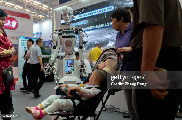 People are communicating with robots on the 2nd World Intelligence Congress, which was held in Tianjin Meijiang Exhibition Center from May 16-18,...