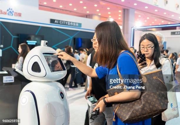 People are communicating with robots on the 2nd World Intelligence Congress, which was held in Tianjin Meijiang Exhibition Center from May 16-18,...
