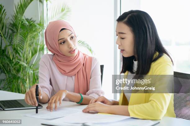 malaysian woman explaining document - malay hijab stock pictures, royalty-free photos & images