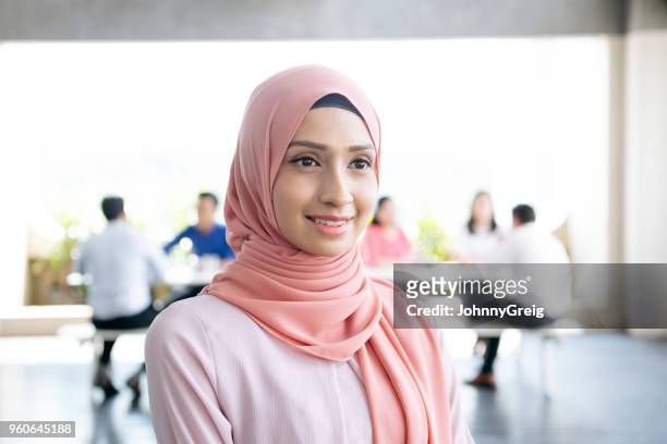 mujer joven alegre en hijab sonriendo y mirando a - velo fotografías e imágenes de stock