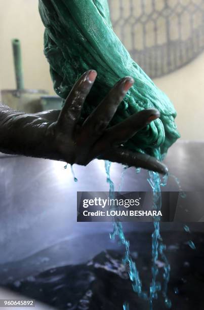 Mohammad al-Rihawi dips silk threads into green dye on January 23, 2018 at his atelier in the Syrian capital Damascus. Civil war has ravaged Syria...