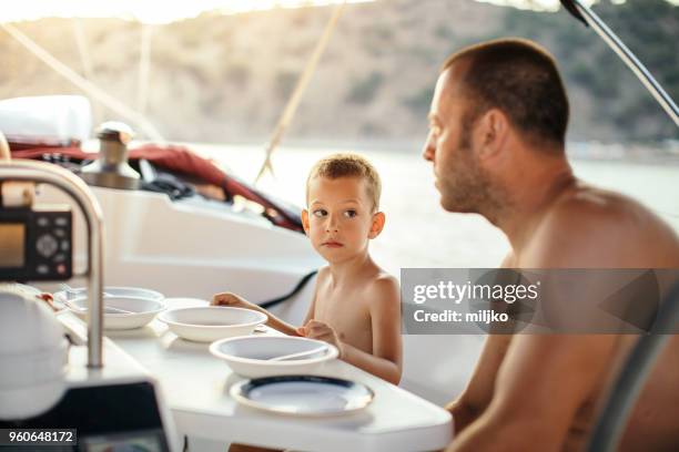 father and his son waiting for lunch on sailboat - miljko stock pictures, royalty-free photos & images