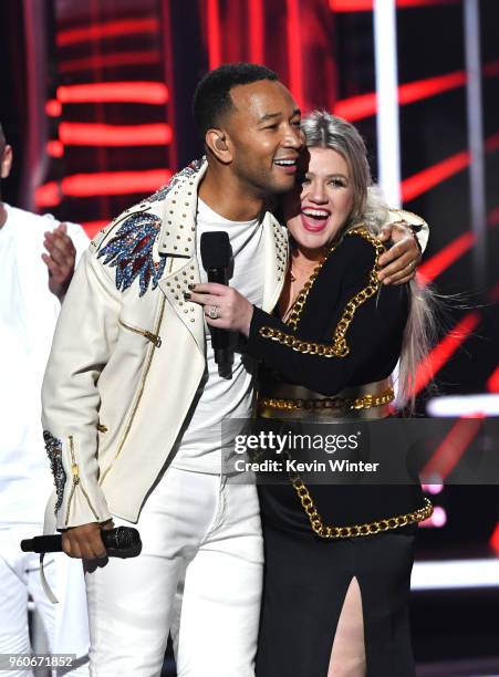 Recording artist John Legend and host Kelly Clarkson embrace onstage during the 2018 Billboard Music Awards at MGM Grand Garden Arena on May 20, 2018...
