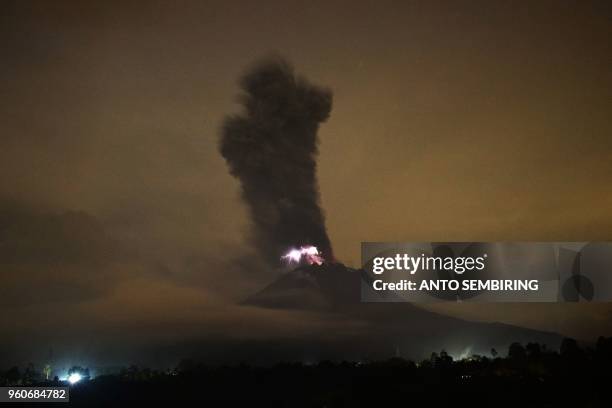 This picture taken on May 20, 2018 shows the Mount Sinabung volcano spewing ash into the air and lightning from its crater in Karo. - Sinabung roared...