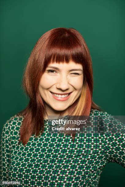 rothaarige frau zwinkert auf grünem hintergrund - zwinkern stock-fotos und bilder