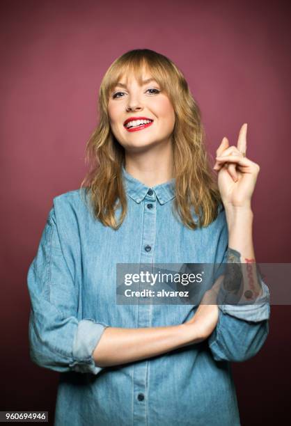 smiling young woman pointing on pink background - gesturing stock pictures, royalty-free photos & images