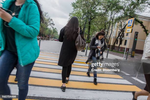 Pedestrians using smartphones cross a road in Almaty, Kazakhstan, on Thursday, April 26, 2018. By juggling its reserves to reduce the pain of...