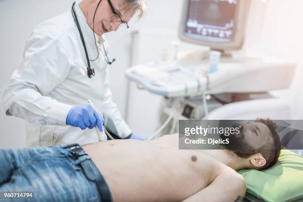 mid adult man on ultrasound. - male stomach stock pictures, royalty-free photos & images