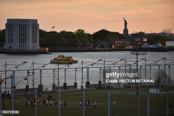 People play a soccer match during sunset at Brooklyn Bridge Park in New York City on May 20 against the background of the Statue of Liberty.