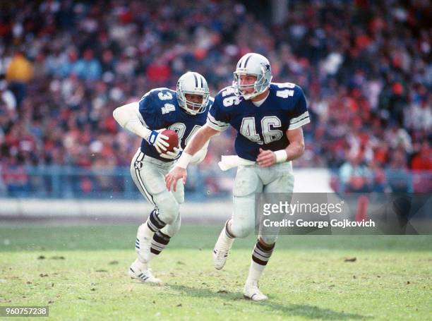 Running back Herschel Walker of the Dallas Cowboys runs with the football behind the blocking of fullback Todd Fowler during a game against the...