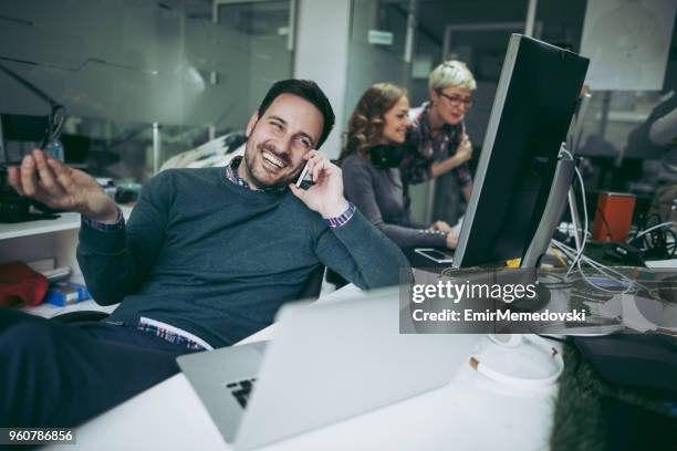 computer programmer using mobile phone while working on laptop - web programmer stock pictures, royalty-free photos & images