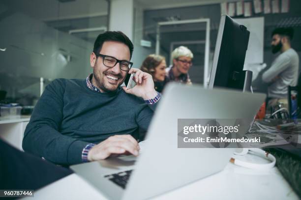 computer programmer using mobile phone while working on laptop - web programmer stock pictures, royalty-free photos & images