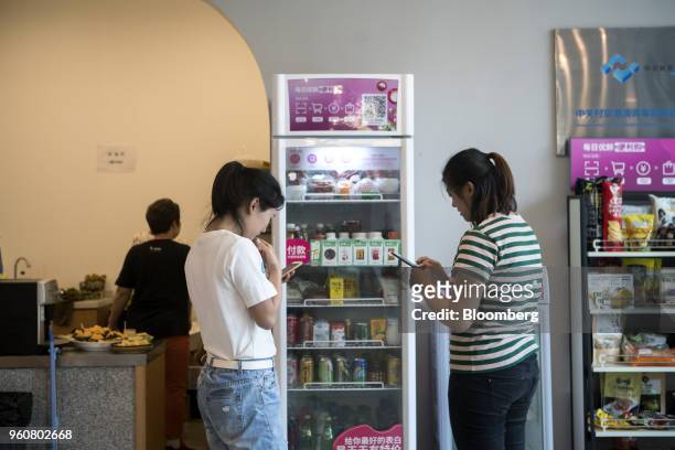 Customers use smartphones to purchase products from a Mr. Fresh unmanned kiosk inside the offices of its affiliate Miss Fresh in Beijing, China, on...