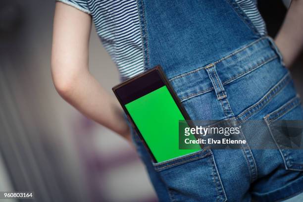 child with mobile phone in back pocket displaying a green screen - phone in back pocket stock pictures, royalty-free photos & images