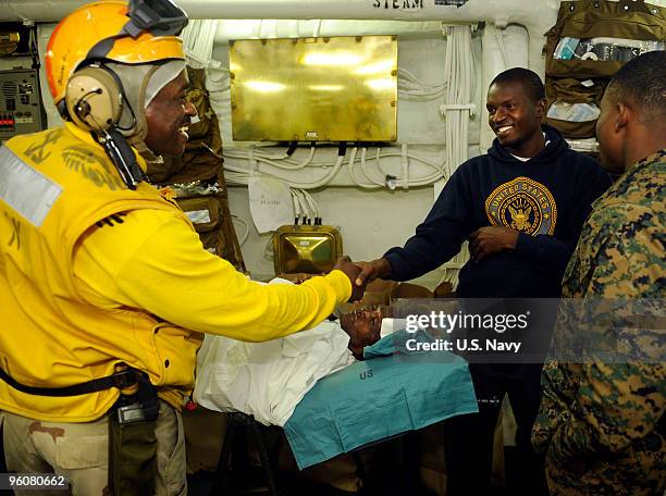 Haitian man shakes hands with Chief Warrant Officer Wilfrid Bossous, a Haiti native assigned to the amphibious assault ship USS Bataan , shortly...