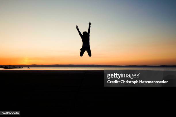 jumping woman on coastline - floating piers ストックフォトと画像