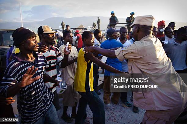 Haitians fight for aid at an old military airfield in Port-au-Prince on January 23, 2010. UN troops fired warning shots and sprayed tear gas on...