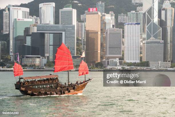 a chinese junk carries tourist across the famous victoria harbor in hong kong - hong kong junk boat stock pictures, royalty-free photos & images