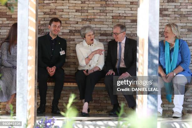 Britain's Prime Minister Theresa May talks with designer Tom Massey in his Lemon Tree Trust Garden, inspired by the resilience, determination and...