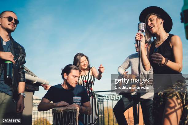 friends on the rooftop listening to live music performance group - maxim musician stock pictures, royalty-free photos & images