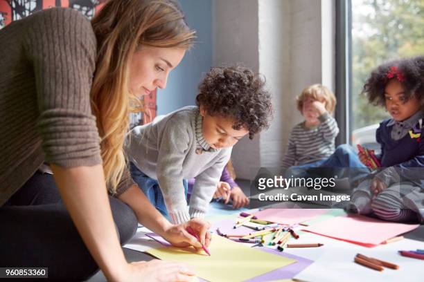 teacher drawing with students on floor at preschool - day care stock-fotos und bilder