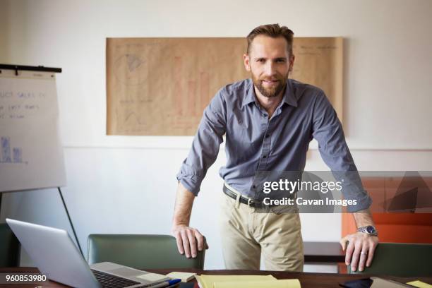 portrait of businessman standing in office - leaning stock pictures, royalty-free photos & images