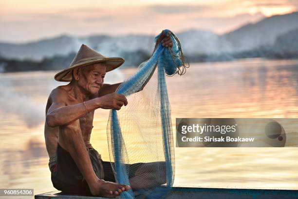 old fisherman fishing in myanmar happily. - fishing village photos et images de collection