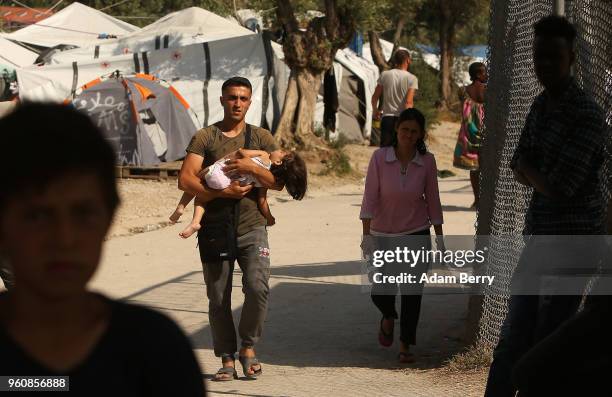 Refugee carries a child through the Moria refugee camp on May 20, 2018 in Mytilene, Greece. Despite being built to hold only 2,500 people, the camp...