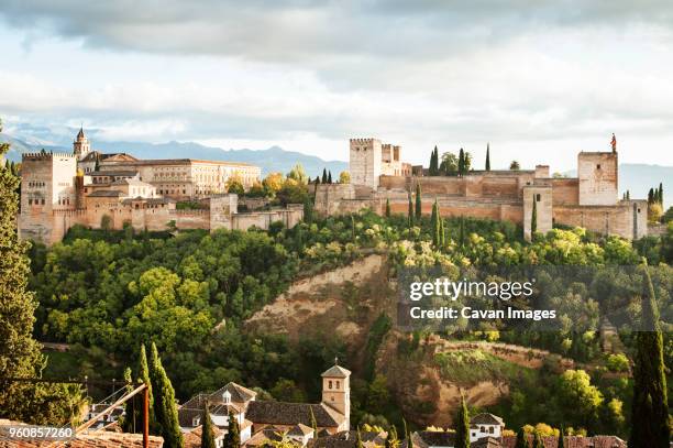 view of buildings on hill against cloudy sky - algarve stock pictures, royalty-free photos & images