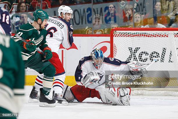 Steve Mason makes a blocker save as his Columbus Blue Jackets teammate Derick Brassard prevents Kyle Brodziak of the Minnesota Wild from getting to...