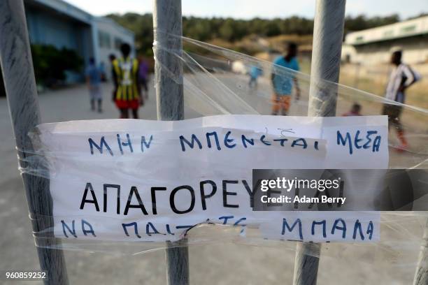 Sign reads 'No Trespassing Or Ball Playing' in Greek as refugees play soccer on a makeshift soccer field in a parking lot outside the Moria refugee...