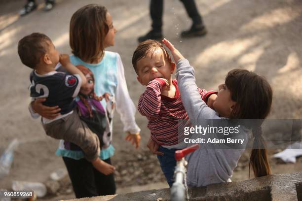 Syrian refugee child cleans her brother's face at the Moria refugee camp on May 20, 2018 in Mytilene, Greece. Despite being built to hold only 2,500...