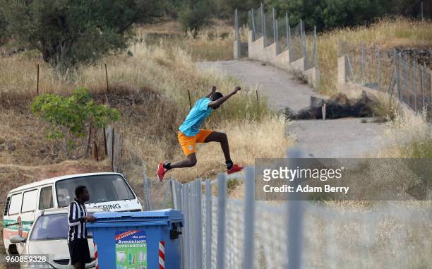 An African refugee jumps a fence while playing soccer to retrieve the ball after it went over the fence of a makeshift soccer field on a private,...
