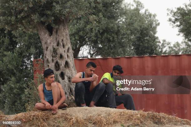 Refugees sit outside the Moria refugee camp on May 20, 2018 in Mytilene, Greece. Despite being built to hold only 2,500 people, the camp on the Greek...