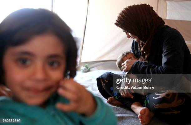 Syrian mother breastfeeds her son in their tent at the Moria refugee camp on May 20, 2018 in Mytilene, Greece. Despite being built to hold only 2,500...